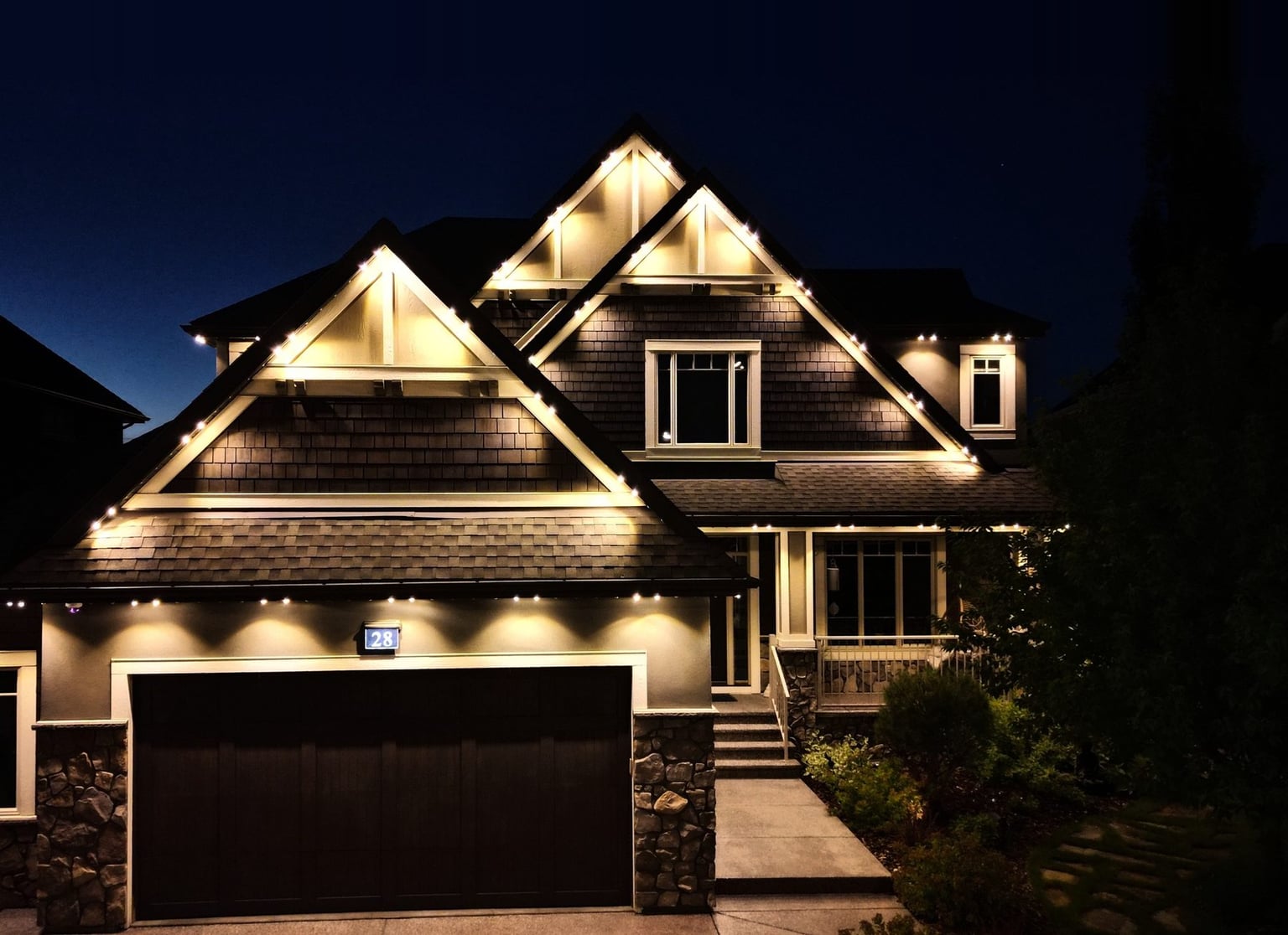 A home with warm white light tracing its rooflines